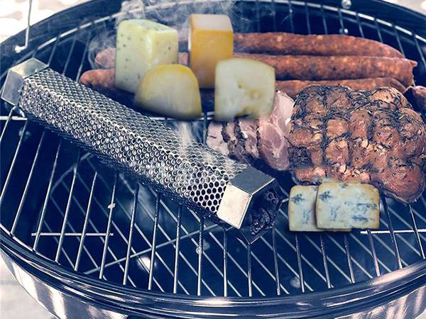 A pellet smoker tube is placed next to the grilled food.